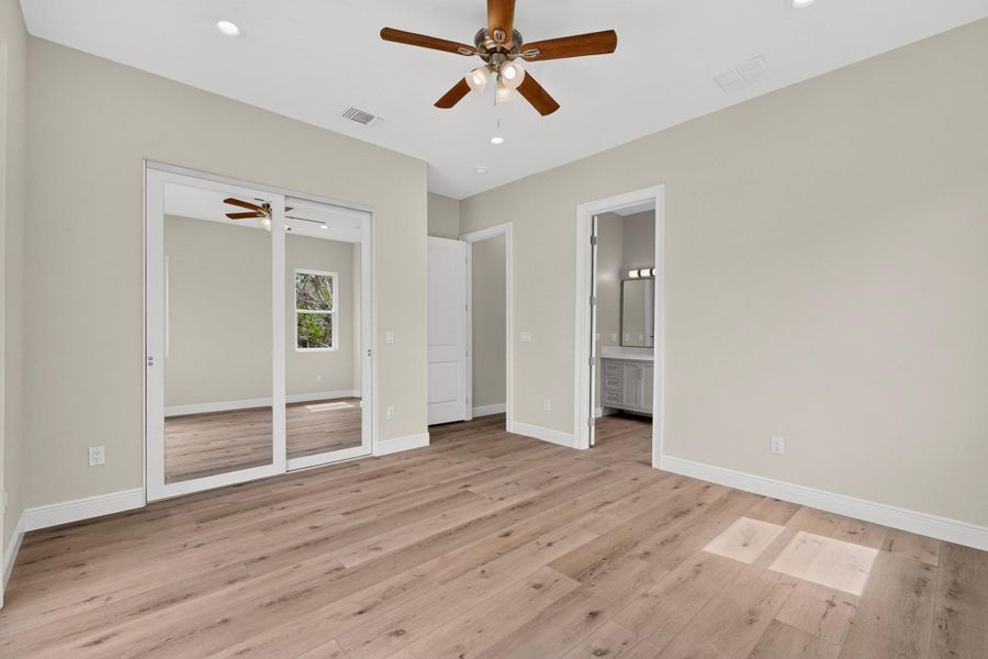 Smooth wood-look flooring and tall doorways define this modern bedroom space.
