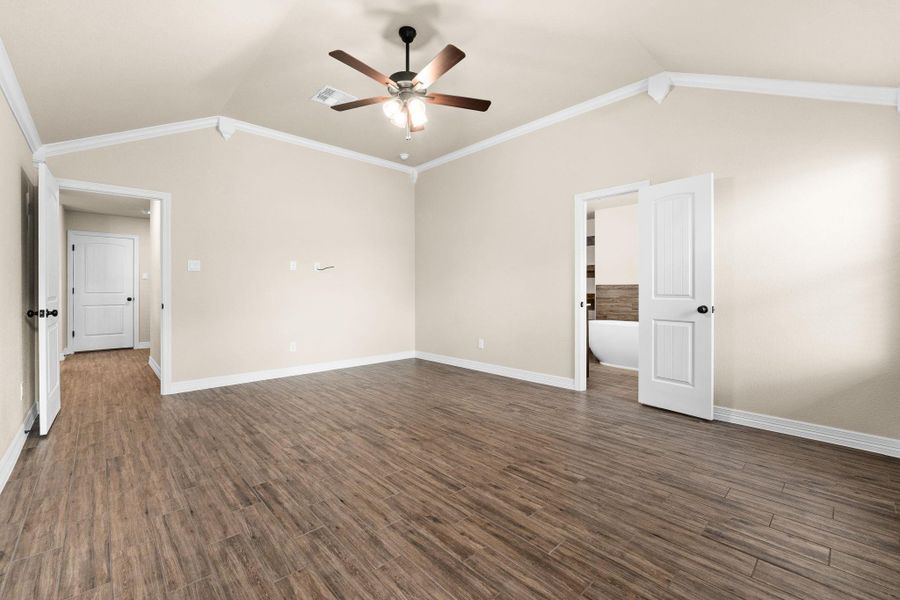 Empty room featuring crown molding, dark wood like tile floors, lofted ceiling, and a ceiling fan Empty room featuring crown molding, dark wood like tile floors, lofted ceiling, and a ceiling fan