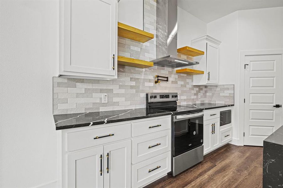 Kitchen with stainless steel electric range oven, open shelves, wall chimney range hood, and white cabinetry