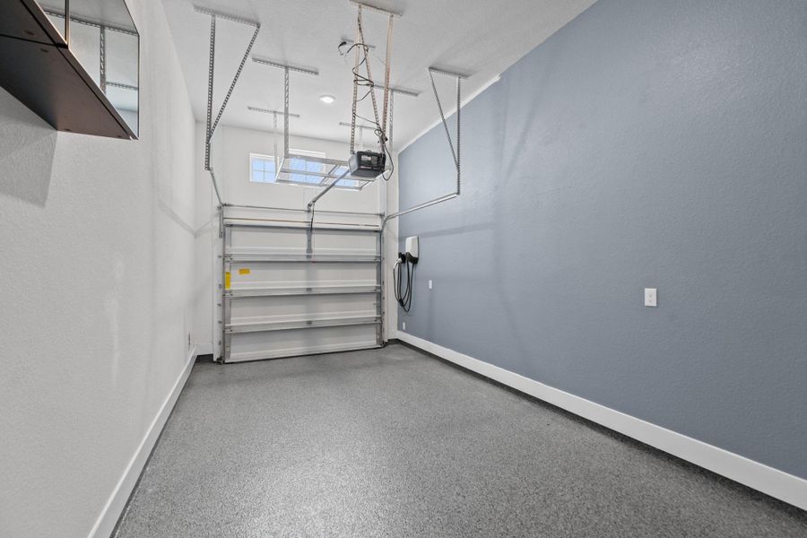Thsi garage has epoxy garage flooring, an EV charger and overhead garage storage.