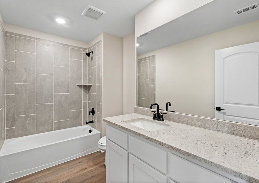 The secondary bathroom has a large vanity space and shower-tub combo.