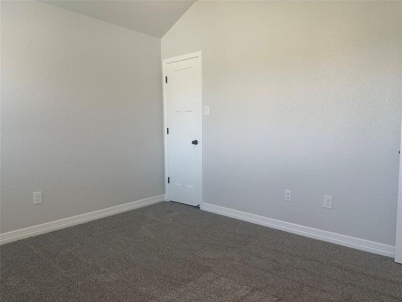 Empty room featuring vaulted ceiling and dark carpet