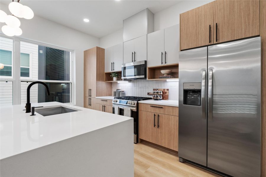 Wake up to sunlight pouring through oversized windows as you prep at this striking island—complete with a matte black faucet, deep undermount sink, and seamless quartz countertops. Designed for daily life and entertaining alike, it’s the perfect perch for morning coffee, casual conversations, or catching golden hour.