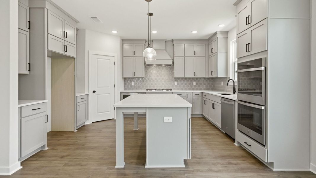 Kitchen with quartz countertops, tile backsplash, and pendant lighting
