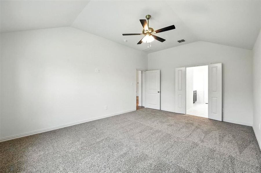 Unfurnished bedroom featuring vaulted ceiling, carpet floors, and ceiling fan