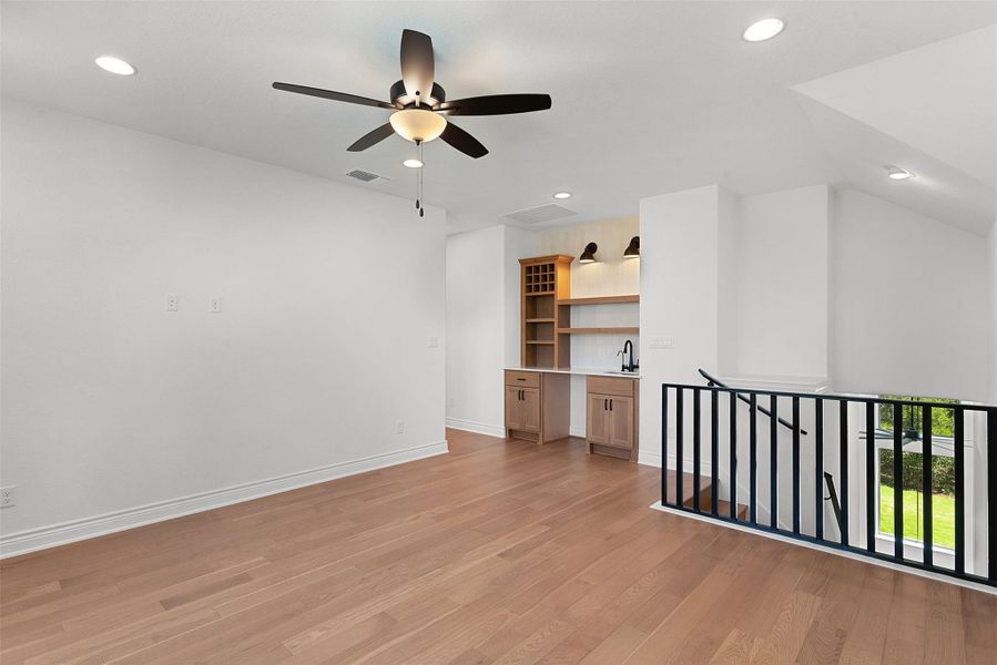 An inviting open-concept area boasts rich hardwood floors and a functional wet bar.