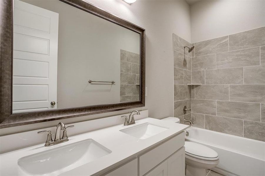 Full bathroom with toilet, tiled shower / bath combo, and dual bowl vanity