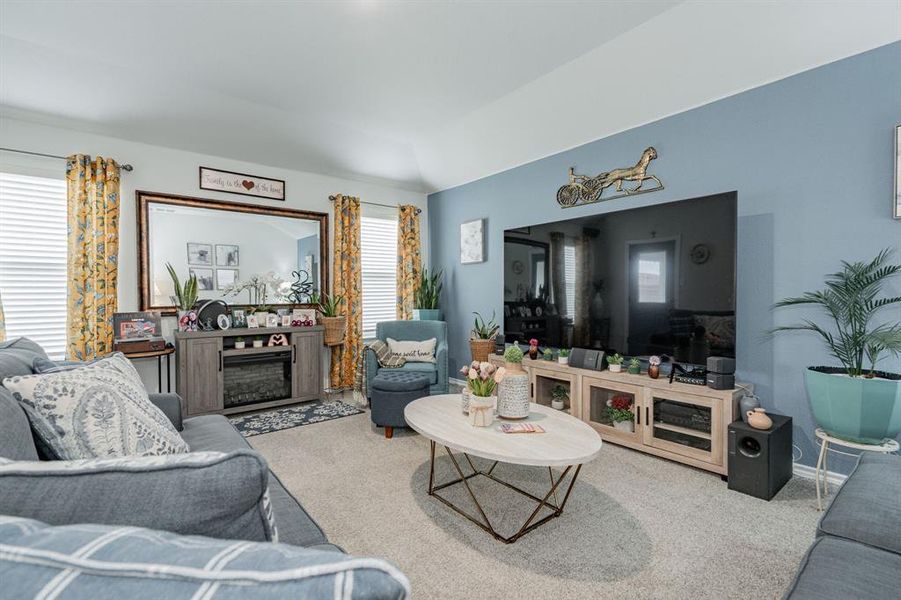 Living area featuring a fireplace, lofted ceiling, carpet, and baseboards