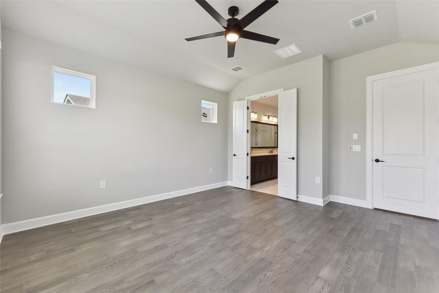 Unfurnished bedroom featuring lofted ceiling, dark wood-type flooring, baseboards, ensuite bathroom, and a ceiling fan Unfurnished bedroom featuring lofted ceiling, dark wood-type flooring, baseboards, ensuite bathroom, and a ceiling fan