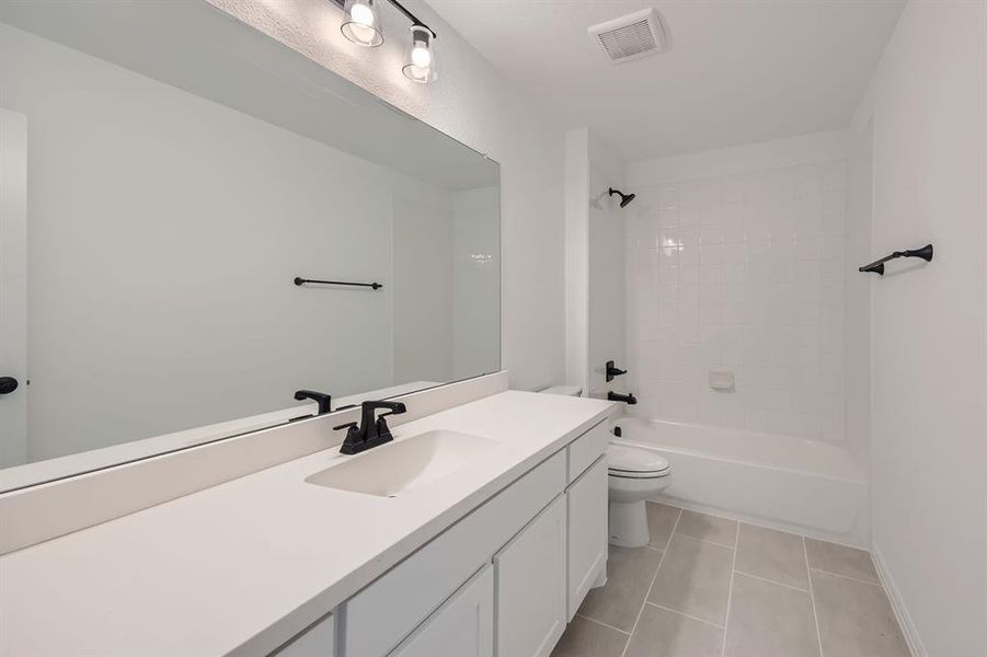 Full bathroom with tile patterned flooring, vanity, toilet, and tiled shower / bath