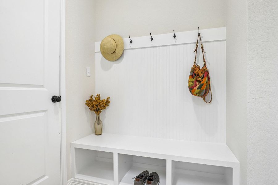 A convenient mudroom entryway offers built-in storage cubbies and wall hooks for effortless organization.