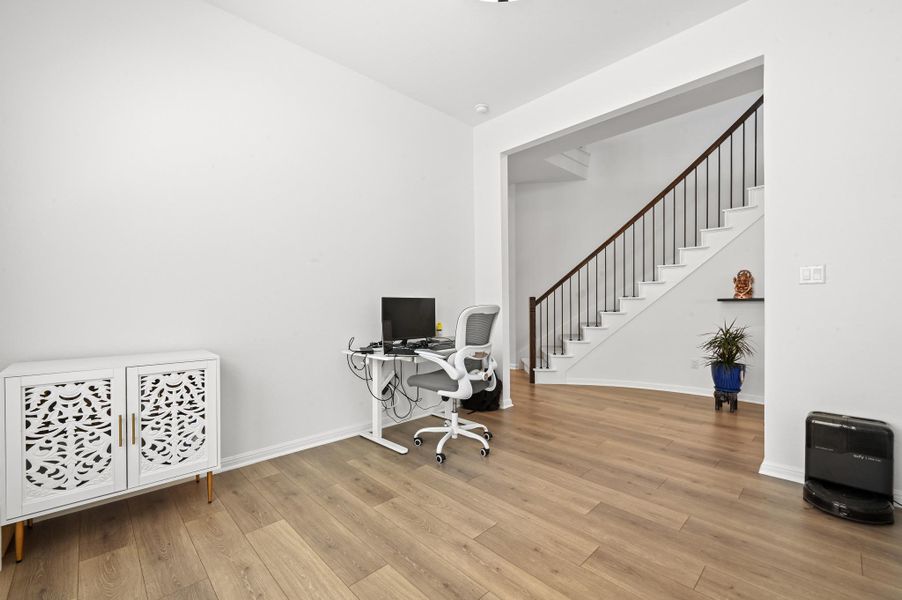Smooth wood floors flow seamlessly through this versatile flex space next to the staircase.