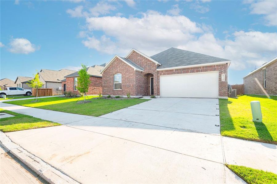 Single-story brick exterior featuring an arched entryway and a two-car garage Single-story brick exterior featuring an arched entryway and a two-car garage
