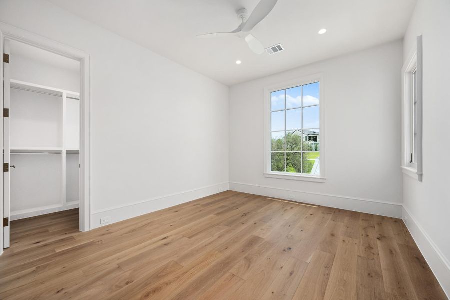 Hardwood floors and a large window illuminate this airy primary bedroom.
