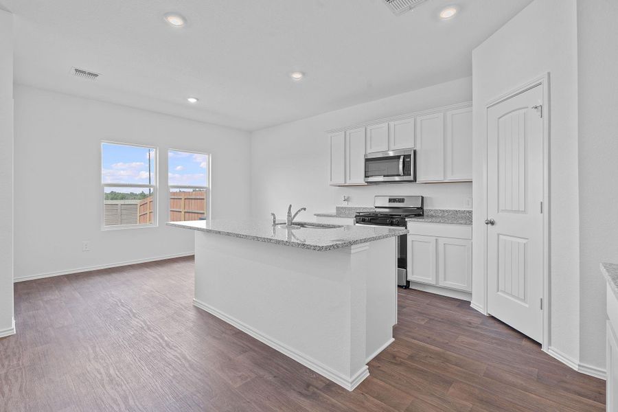 Kitchen with white cabinets, appliances with stainless steel finishes, light stone counters, dark wood-style flooring, and recessed lighting Kitchen with white cabinets, appliances with stainless steel finishes, light stone counters, dark wood-style flooring, and recessed lighting