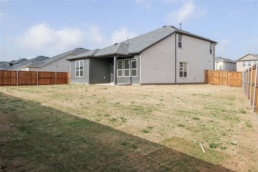 Rear view of property featuring a yard, a fenced backyard, brick siding, and a shingled roof