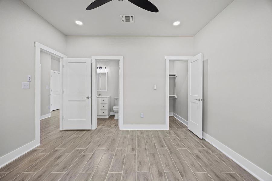 Unfurnished bedroom with a spacious closet, wood finish floors, ensuite bath, recessed lighting, and ceiling fan Unfurnished bedroom with a spacious closet, wood finish floors, ensuite bath, recessed lighting, and ceiling fan