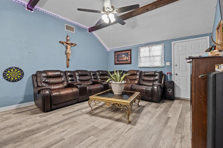 Living room with ceiling fan, light hardwood / wood-style flooring, and lofted ceiling with beams