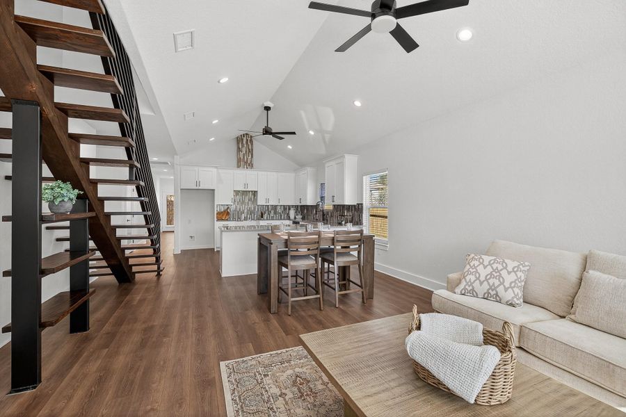 Living area featuring dark wood finished floors, stairs, ceiling fan, high vaulted ceiling, and recessed lighting Living area featuring dark wood finished floors, stairs, ceiling fan, high vaulted ceiling, and recessed lighting