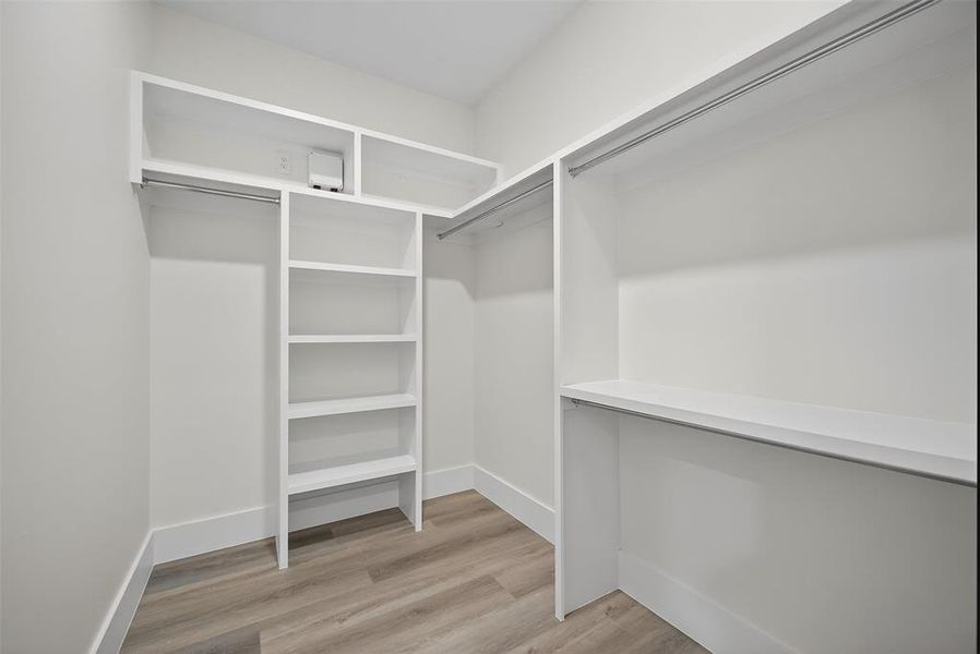 Walk in closet with light wood-type flooring