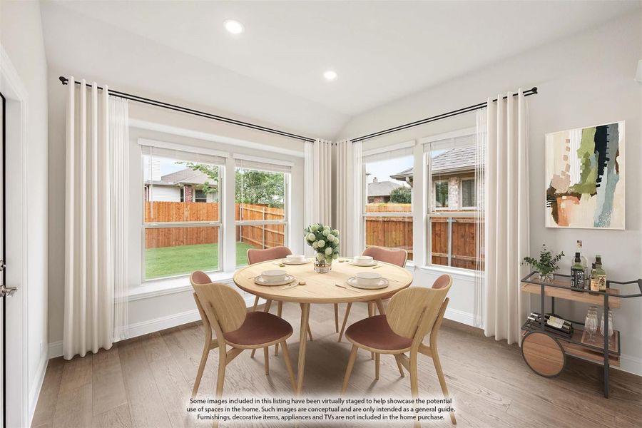 Bright dining nook with round wood table, four chairs, large windows, and hardwood floors