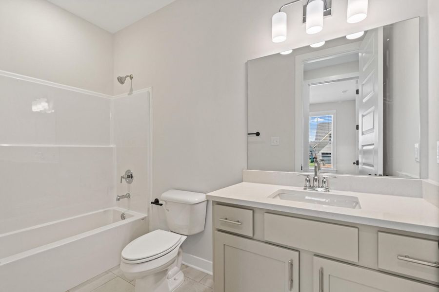 Bathroom featuring a white integrated tub and shower combination, a white toilet, and a vanity with a white countertop, an undermount sink, and chrome fixtures Bathroom featuring a white integrated tub and shower combination, a white toilet, and a vanity with a white countertop, an undermount sink, and chrome fixtures