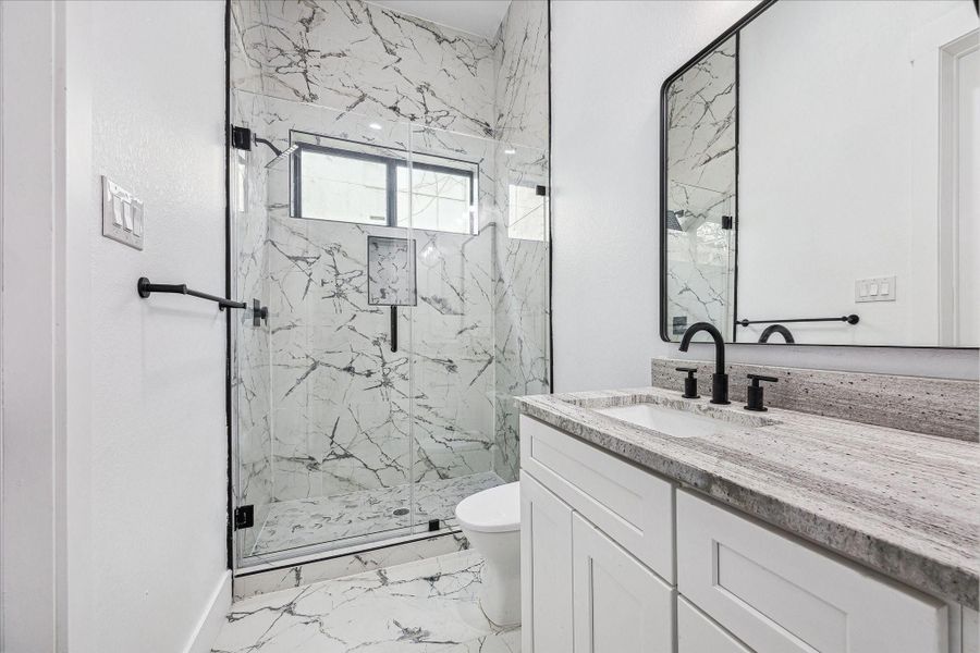 The downstairs bathroom features a sleek, modern shower with premium fixtures and elegant finishes, combining style and functionality.