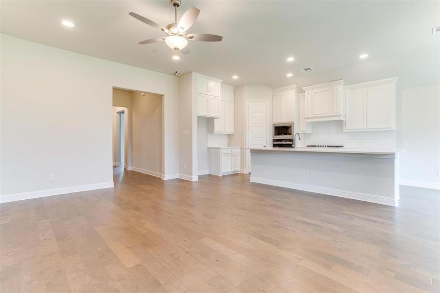 Unfurnished living room featuring sink, ceiling fan, and light wood-type flooring