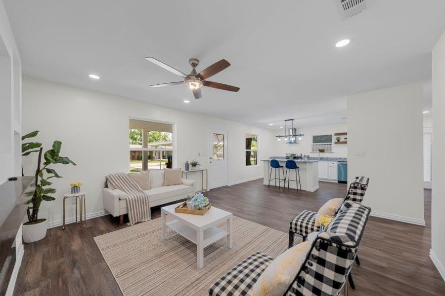 Living room featuring plenty of natural light, ceiling fan, recessed lighting, a chandelier, and dark wood-style floors Living room featuring plenty of natural light, ceiling fan, recessed lighting, a chandelier, and dark wood-style floors