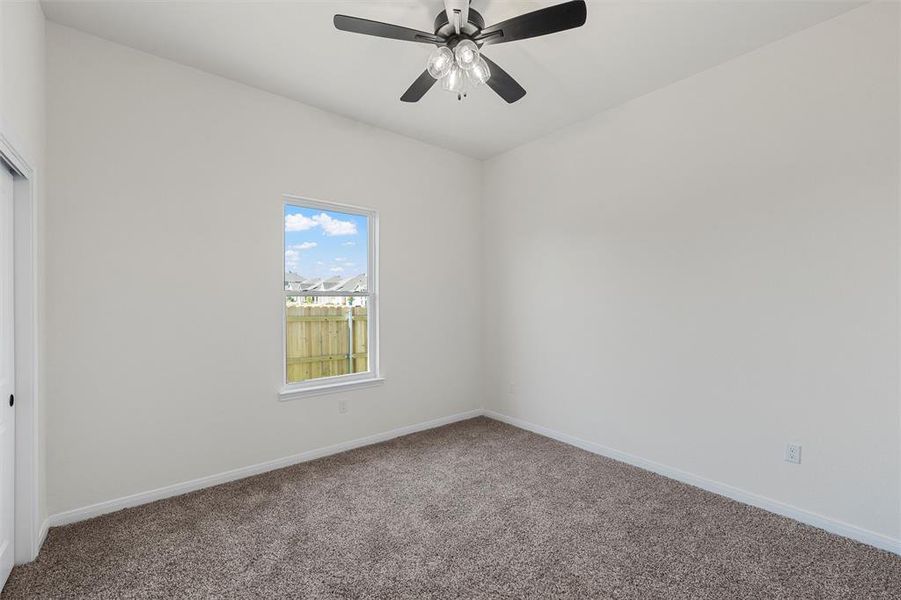 Carpeted spare room featuring baseboards and ceiling fan