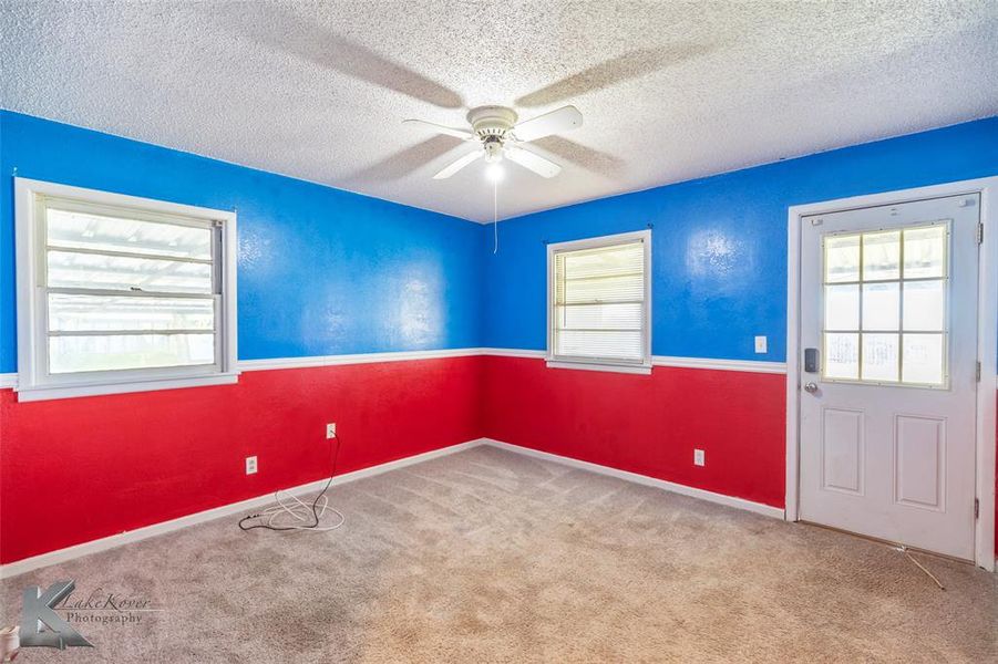 Unfurnished room featuring a textured ceiling, carpet floors, and a ceiling fan