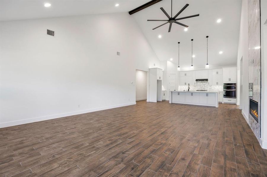Expansive living area featuring vaulted ceilings, wood-finish flooring, and recessed lighting Expansive living area featuring vaulted ceilings, wood-finish flooring, and recessed lighting