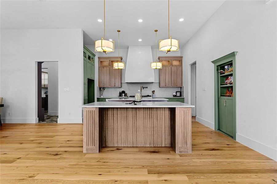 Kitchen with glass insert cabinets, 2 center islands, one island with farm sink, quartz backsplash, pendant lighting, gold figures. Pantry is behind the decorative door. Kitchen with glass insert cabinets, 2 center islands, one island with farm sink, quartz backsplash, pendant lighting, gold figures. Pantry is behind the decorative door.