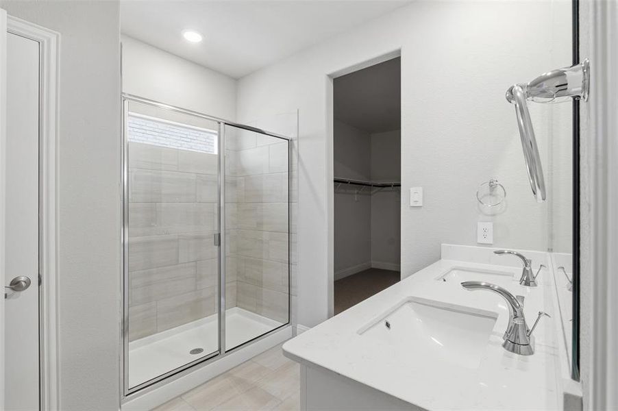 Bathroom featuring a shower with glass enclosure, a dual vanity with undermount sinks, and a walk-in closet