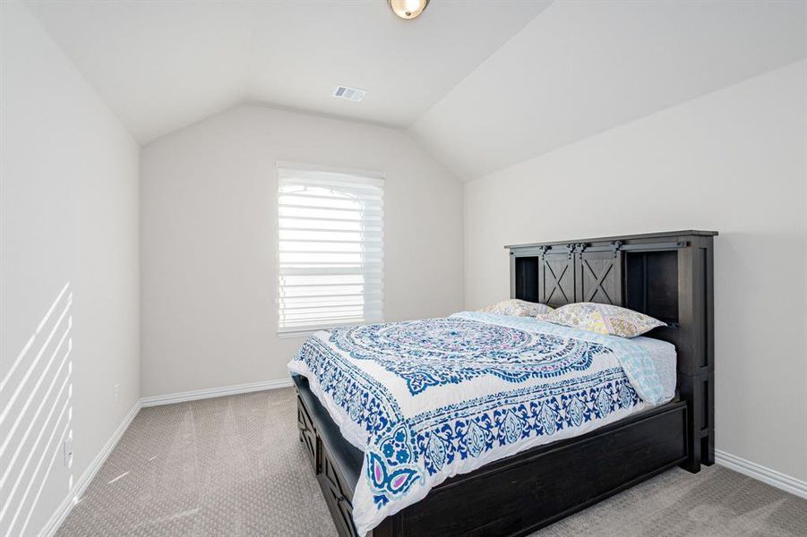 Bedroom with light colored carpet and vaulted ceiling