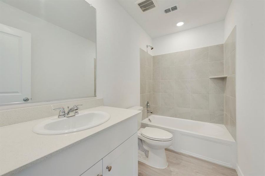 Full bathroom featuring vanity, toilet, tiled shower / bath, and hardwood / wood-style flooring