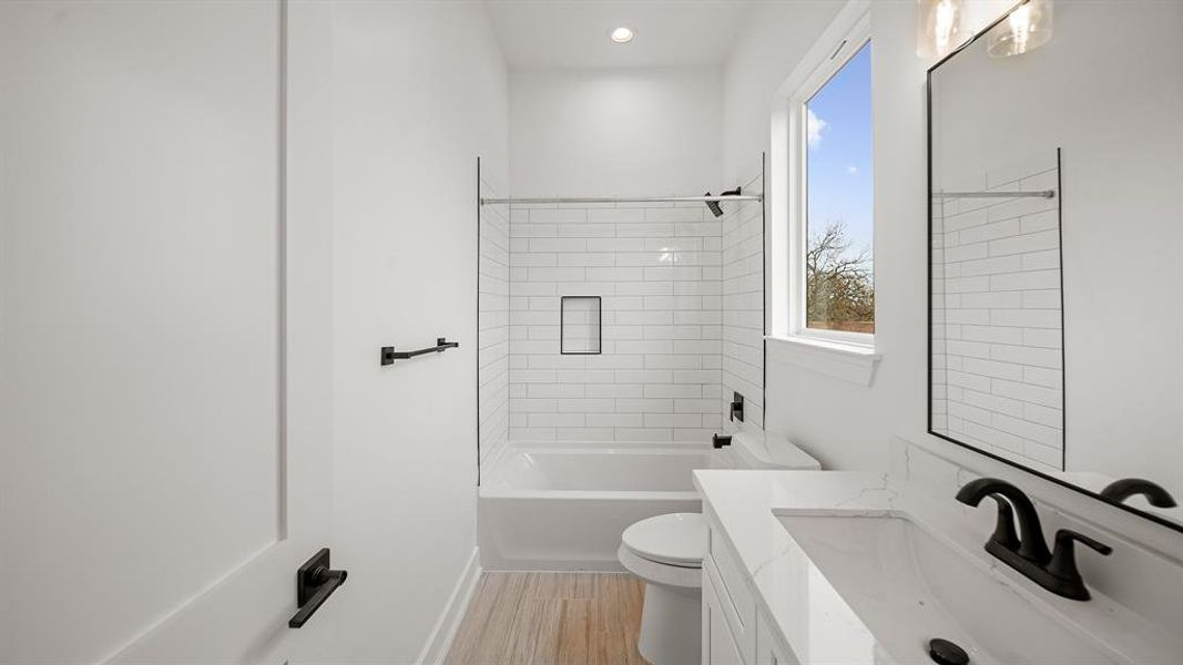 This bathroom is complete with tile floors, soft closing drawers, granite countertops, recessed lighting, and a shower/tub combo.