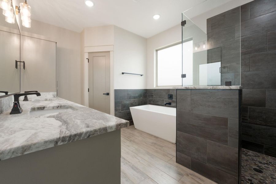 Full bathroom with double vanity, a soaking tub, walk in shower, recessed lighting, and light wood-type flooring