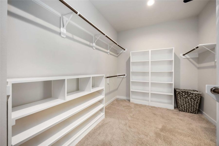 Massive walk-in primary closet with built-in shelving and abundant storage space. Massive walk-in primary closet with built-in shelving and abundant storage space.