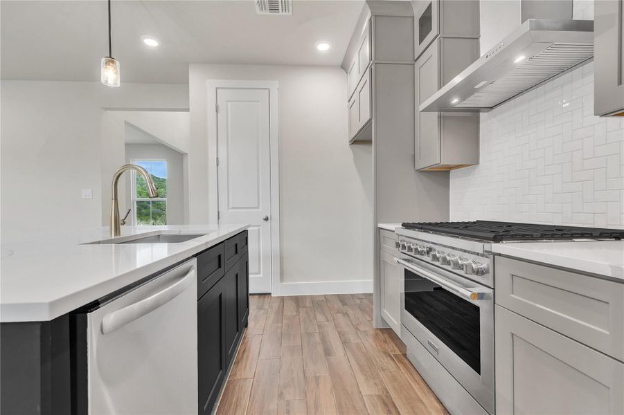 A well-appointed kitchen features a large island, stainless steel appliances, and wood flooring.