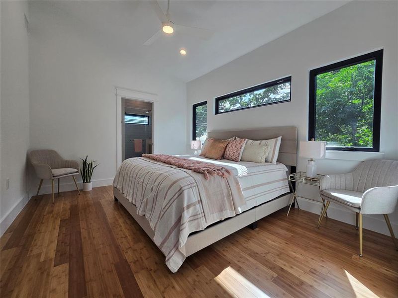 Primary bedroom with a tall vaulted ceiling and lots of natural light through many windows.