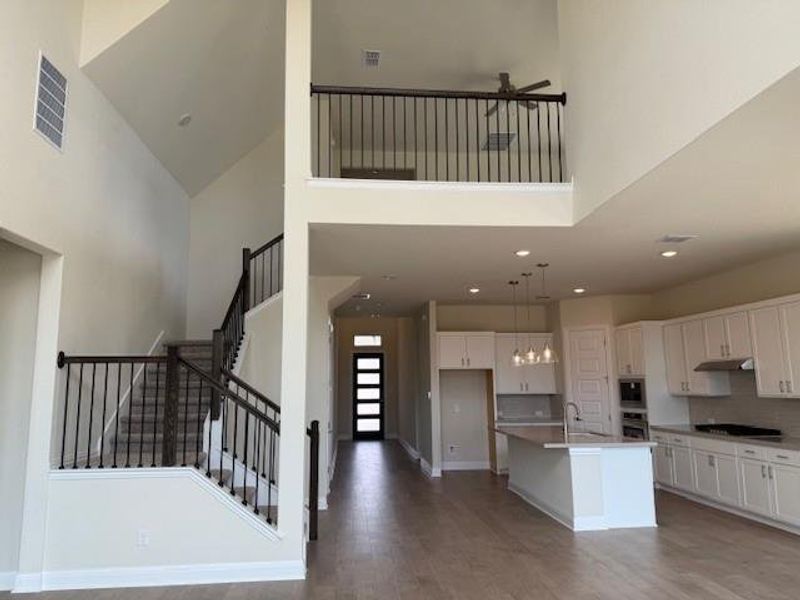 Kitchen featuring a high ceiling, wood finished floors, white cabinetry, backsplash, and ceiling fan Kitchen featuring a high ceiling, wood finished floors, white cabinetry, backsplash, and ceiling fan