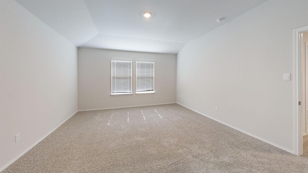 Empty room featuring light colored carpet and vaulted ceiling