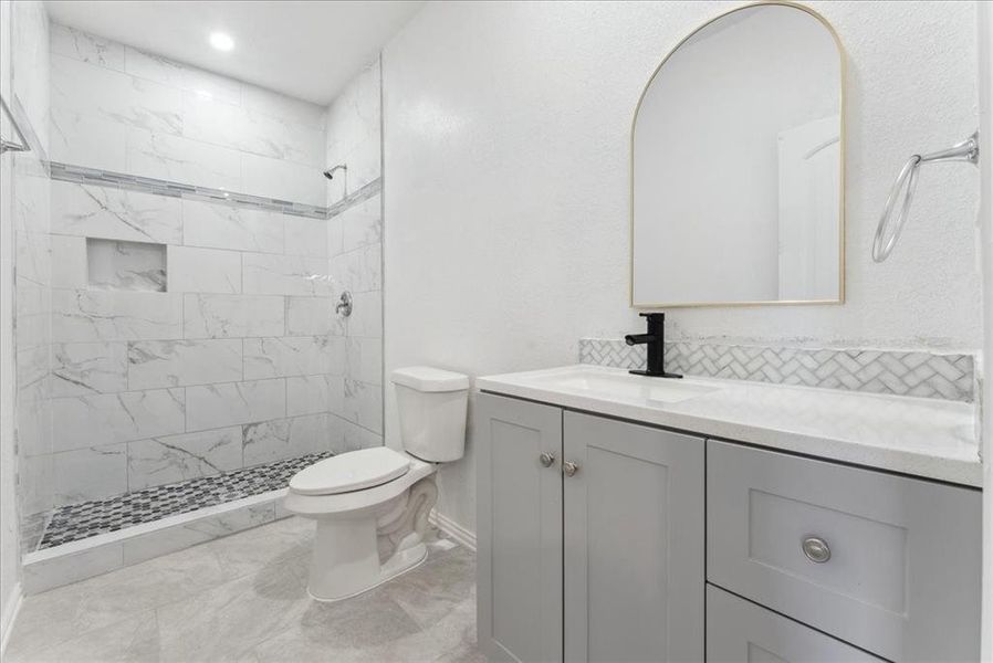 Full bath with tiled shower, backsplash, vanity, and toilet