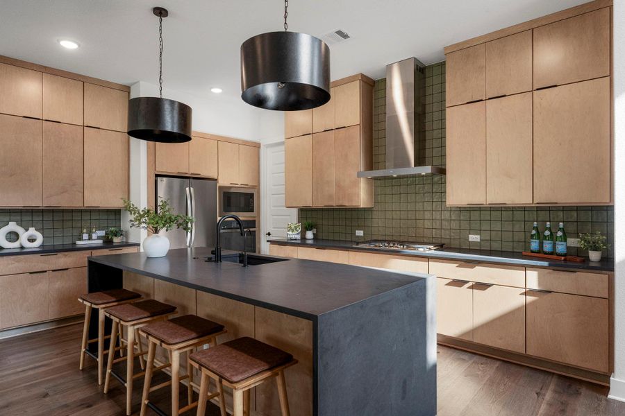 Culinary creations come to life in this modern kitchen featuring a vast island and elegant overhead lighting.