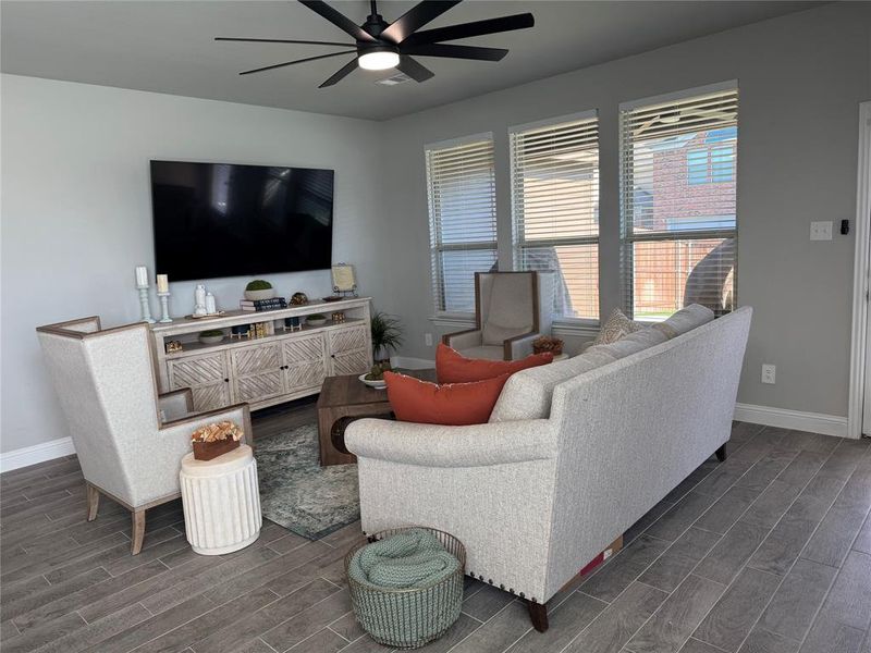 Living area featuring wood tiled floors and a ceiling fan Living area featuring wood tiled floors and a ceiling fan