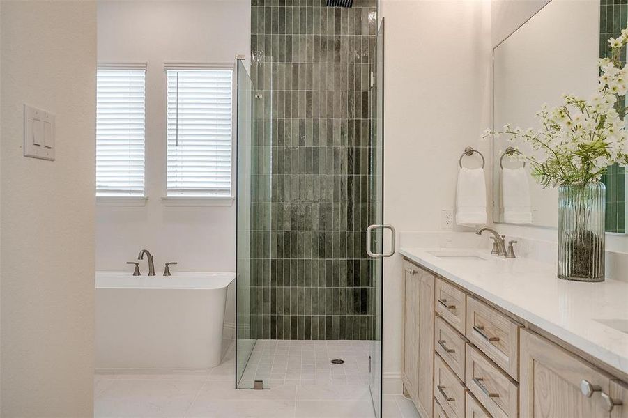 Bathroom with vanity, walk in shower with standard shower head and rain head, freestanding bathtub, and beautiful green tile that compliments the natural stained cabinets.