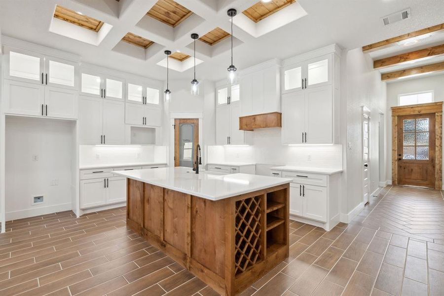 Kitchen featuring white cabinetry, pendant lighting, an island with sink, and a skylight