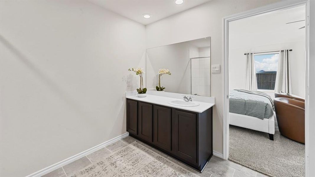 This space features a vanity with a dark wood cabinet, a white countertop, and an integrated sink, complemented by a large mirror