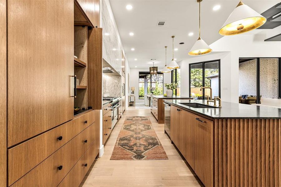 Statement lighting adds dimension and warmth to the kitchen, highlighting the scale of the space while keeping it comfortable for everyday use